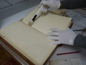 Surface dust being removed from the pages of a case book with a brush.